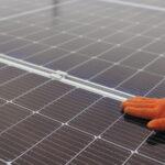 Nahaufnahme einer Hand, die den Betrieb, die Sauberkeit und Oberfläche von Photovoltaik-Solarmodulen überprüft