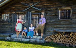 Junge Familie vor einem Ferienhaus in Bayern in einer wunderschönen Berglandschaft